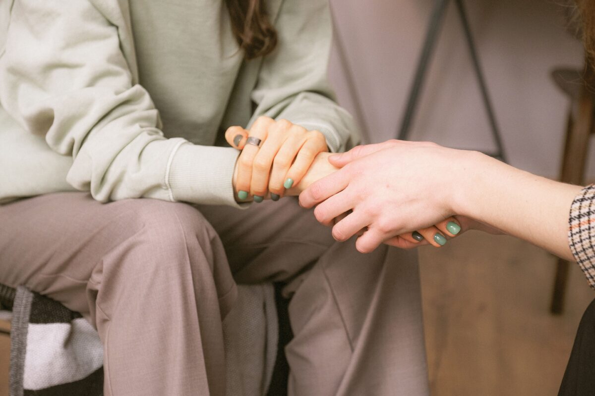deux personnes assises face à face se tenant les mains