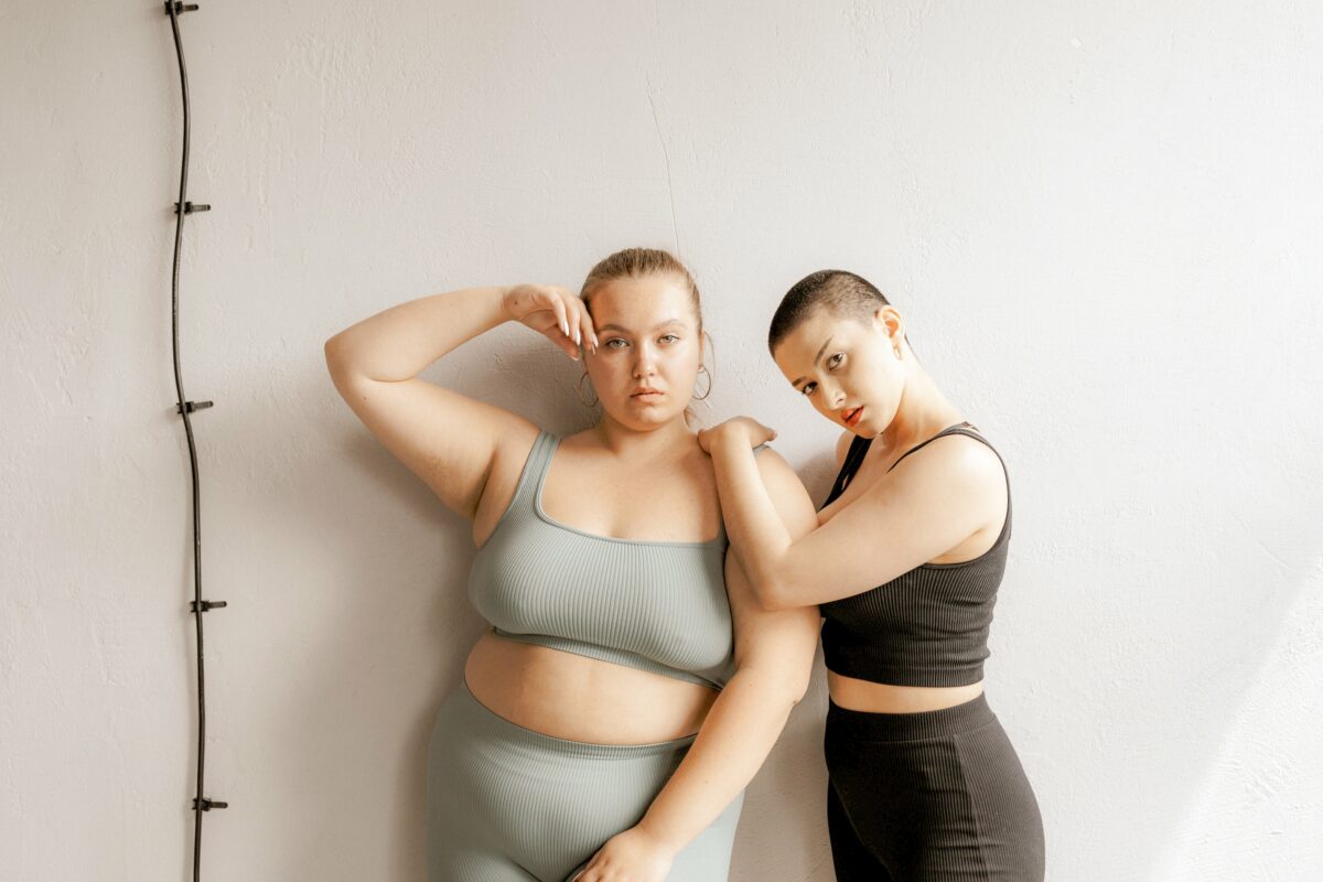 Deux personnes portant un top de sport et des leggings. L'une est appuyée sur l'épaule de l'autre.