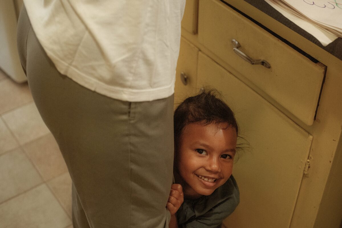 Enfant qui se cache derrière les jambes d'un adulte.