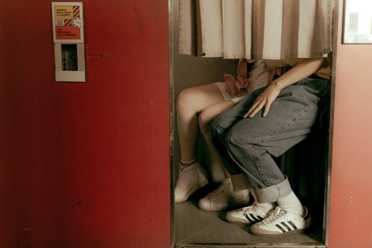 On voit les jambes de deux personnes dans un photomaton