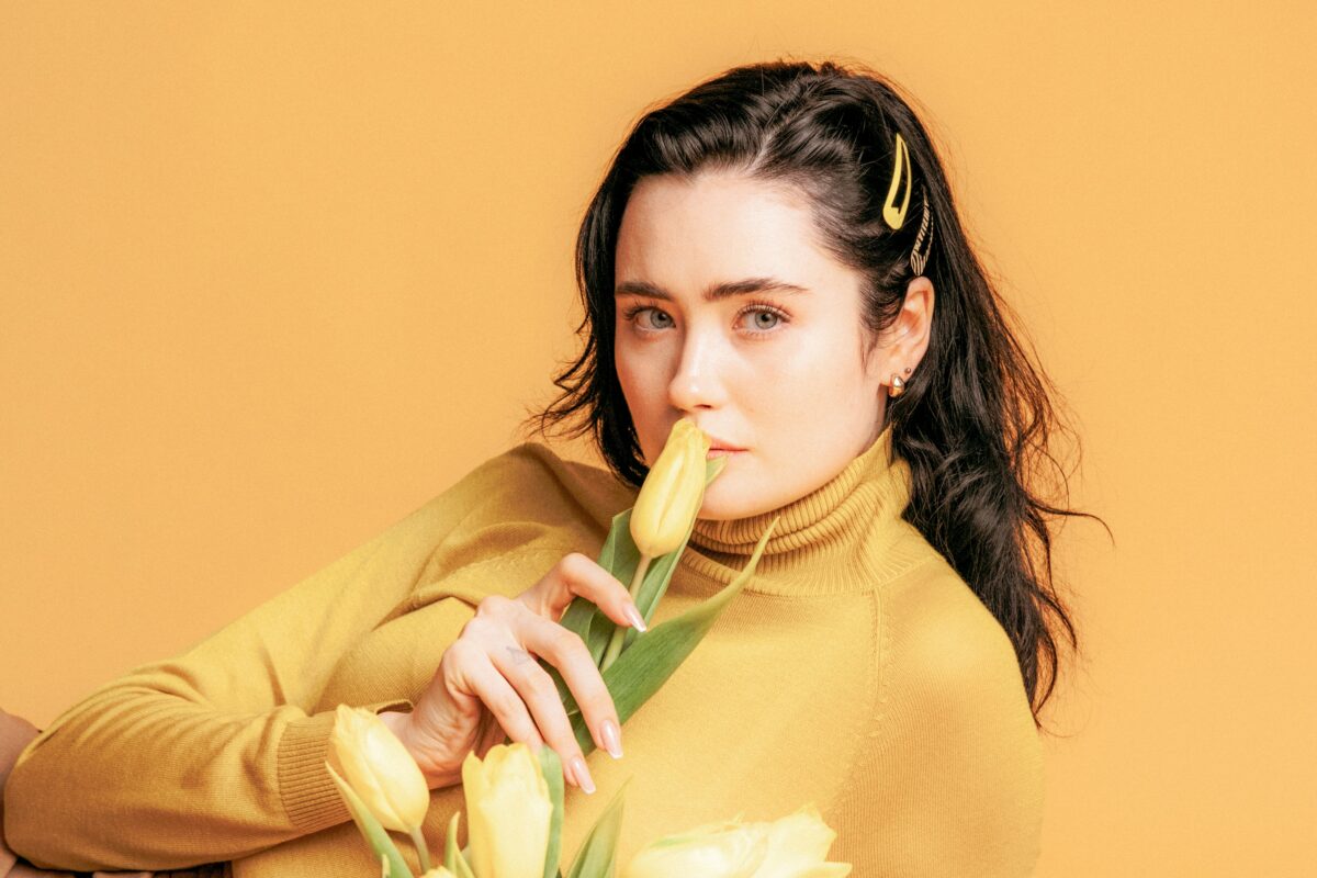 Personne portant un col roulé jaune et qui sent des tulipes jaunes