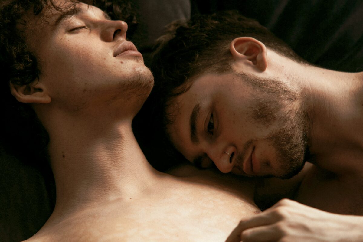 Deux hommes torses nus collés l'un contre l'autre.
