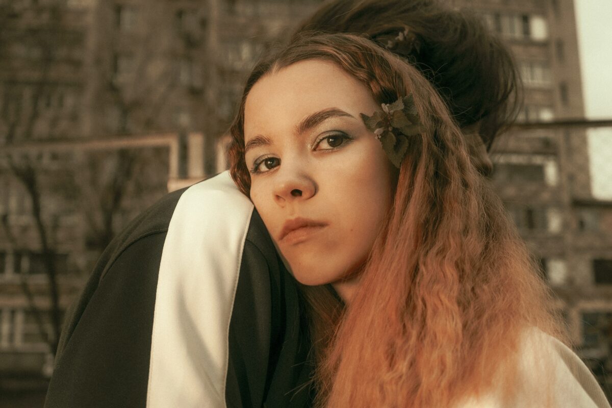 Adolescente qui repose sa tête sur l'épaule d'une autre personne. Elle regarde directement dans la caméra.