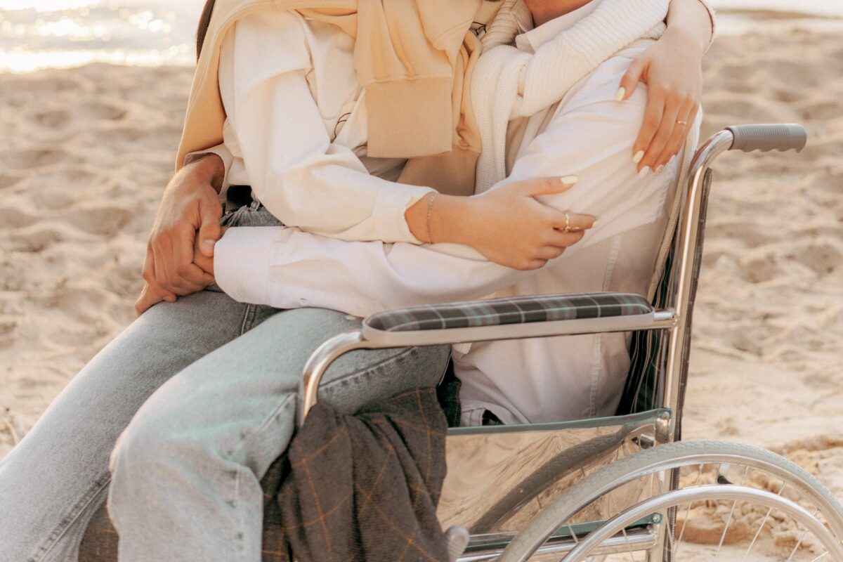 Une personne est assise sur une autre personne en fauteuil roulant.